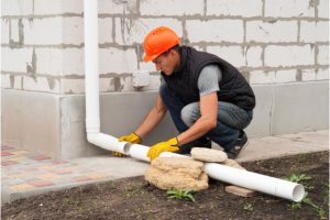 Worker installing gutter system on the side of a home.