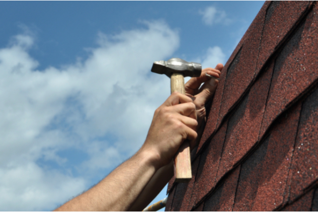 Vallejo roof repairs by worker with a hammer and nail.